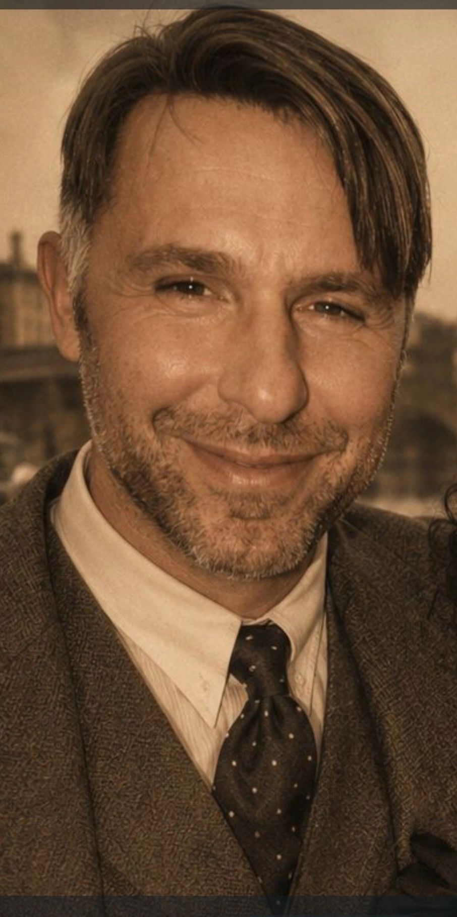Portrait of Mustafa Bayram, founder of A Daim World, smiling in tweed jacket and tie